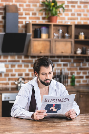 handsome loner businessman reading newspaper in morning at kitchenの写真素材