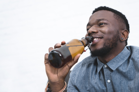 Handsome african american man drinking beer from bottleの写真素材
