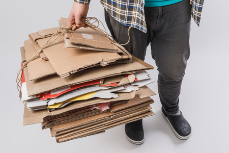 cropped shot of man holding pile of folded cardboard boxes isolated on grey, recycling conceptの写真素材