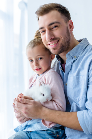 Father and child girl holding white bunnyの写真素材