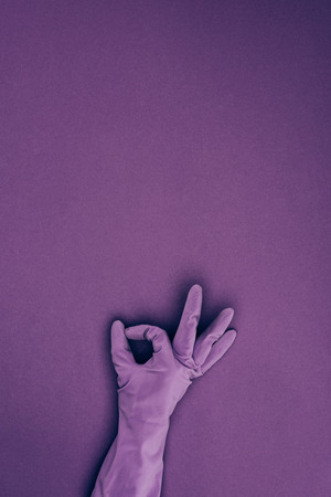 cropped image of woman showing ok sign in rubber protective glove isolated on violetの写真素材