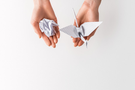 cropped shot of woman holding ball and bird made of paper in hands isolated on grey, environment and recycling conceptの写真素材