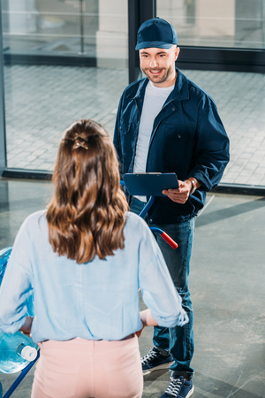 Woman receiving water bottles delivery from loader manの写真素材