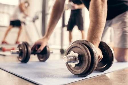 cropped image of sportsman preparing doing push ups on dumbbells in gymの写真素材