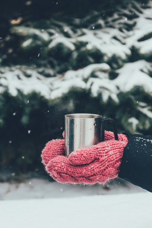 cropped shot of woman holding cup of tea in hands on winter dayの写真素材
