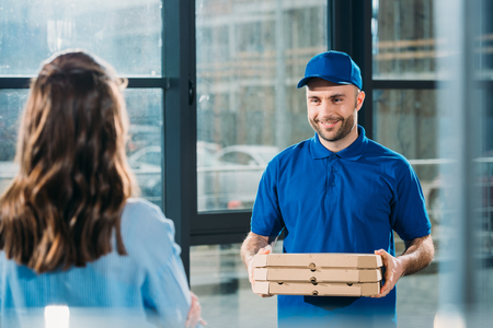 Woman receiving stack of pizzas in boxes from courierの写真素材