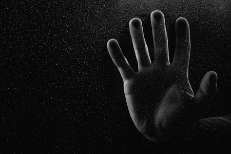 cropped shot of person touching frosted glass with palm in darknessの写真素材