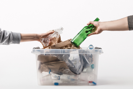 cropped shot of people putting trash into plastic container isolated on white, recycling conceptの写真素材