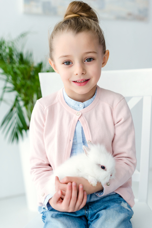 White rabbit sitting on knees of child girlの写真素材