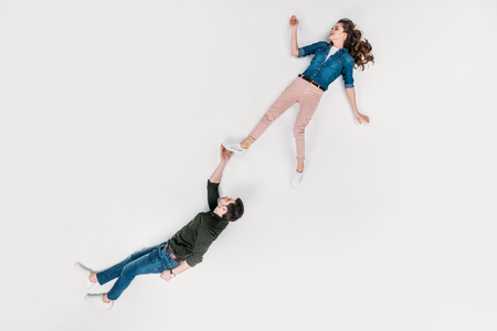 top view of handsome man carrying his girlfriend with one hand isolated on whiteの写真素材