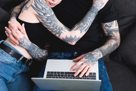 cropped image of tattooed couple using laptopの写真素材