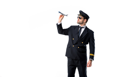 young bearded pilot in uniform and sunglasses with toy plane isolated on whiteの写真素材