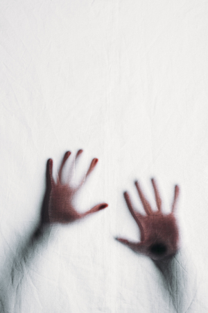 blurry silhouette of human hands touching frosted glassの写真素材