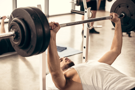 handsome sportsman lifting barbell with heavy weight plates in gymの写真素材