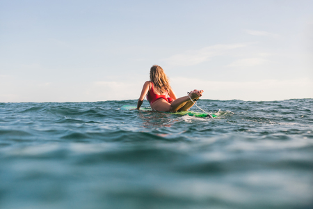 rear view of woman in swimming suit surfing alone in oceanの写真素材