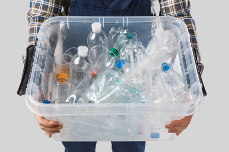 partial view of man holding container with plastic bottles in hands isolated on grey, recycling conceptの写真素材