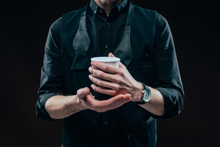 Close-up view of coffee cup in male hands isolated on blackの写真素材