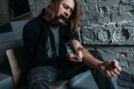 addicted man doing heroin injection on stairsの写真素材