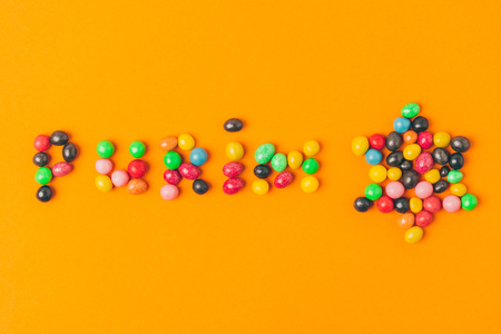 top view of purim lettering made of candies and star isolated on orangeの写真素材