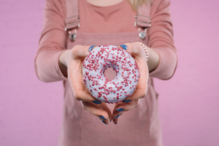 cropped shot of woman showing delicious glazed doughnut at cameraの写真素材