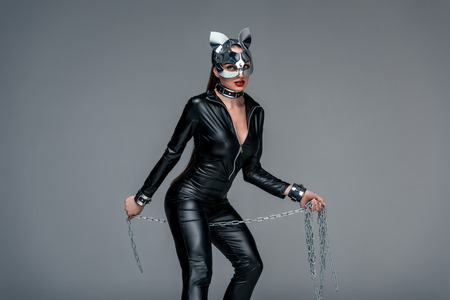 Seductive young woman holding chain isolated on greyの写真素材