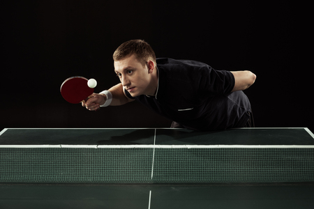 tennis player in uniform playing table tennis isolated on blackの写真素材