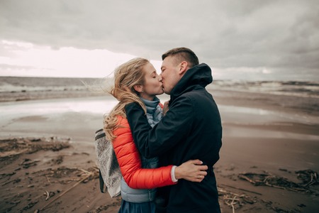 beautiful young couple hugging and kissing on sandy beach of Baltic seaの写真素材