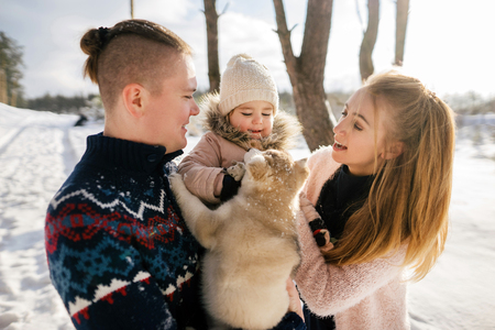 happy young family with one child playing with puppy in winter parkの写真素材