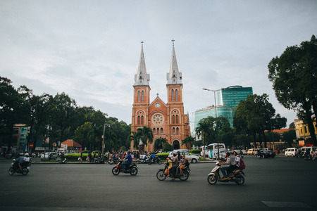 HO CHI MINH, VIETNAM - 03 JANUARY, 2018: people riding motorbikes on road near church and modern buildings in Ho Chi Minh, Vietnamのeditorial素材