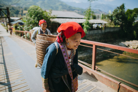 SA PA, VIETNAM - 03 JANUARY, 2018: vietnamese women carrying baskets and walking on bridge in Sa Pa, Vietnamのeditorial素材