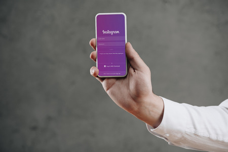 cropped shot of man holding smartphone with instagram website on screenのeditorial素材