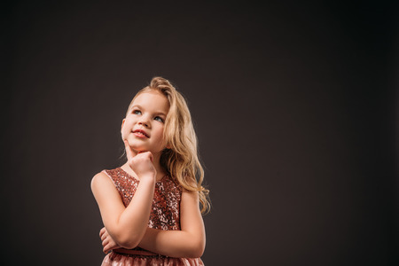 adorable thoughtful child in pink dress, isolated on greyの写真素材