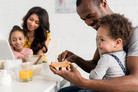 close-up shot of father applying peanut butter on toast for son at kitchenの写真素材