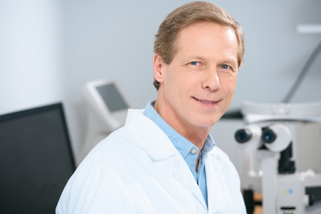 smiling handsome doctor looking at camera in clinicの写真素材