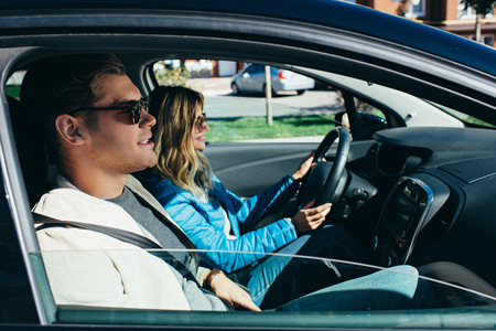 Side view of young woman driving car with boyfriend near by, traveling conceptの写真素材