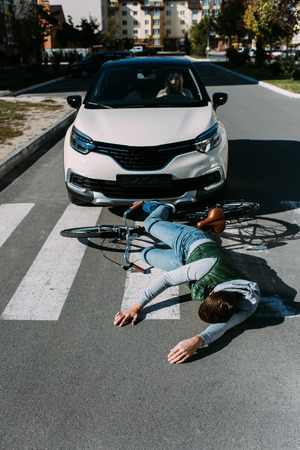 Male bicycle rider hit by woman in car on road, car accident conceptの写真素材