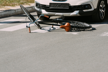 Close up view of broken bicycle and car on road, car accident conceptの写真素材