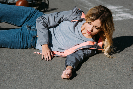 Young woman mowed down by car on road, car accident conceptの写真素材