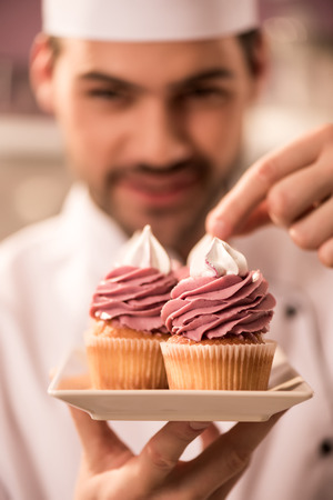 Selective focus of confectioner decorating cupcakes in restaurant kitchenの写真素材