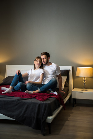 Couple sitting with closed eyes in bedroom with modern interiorの写真素材