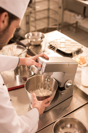 partial view of confectioner making cream for dessert in restaurant kitchenの写真素材