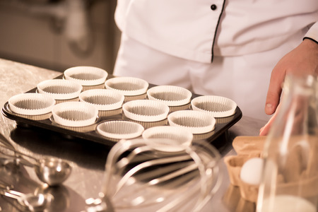 Partial view of confectioner at counter with empty baking formsの写真素材