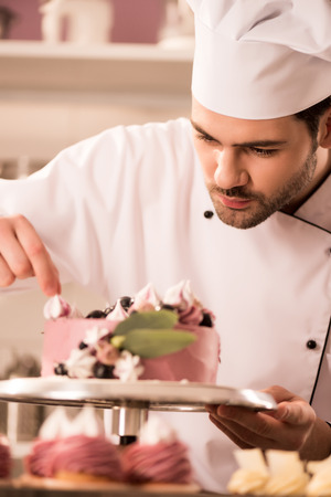 Portrait of confectioner decorating cake in restaurant kitchenの写真素材