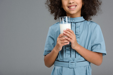 Cropped shot of smiling little child with glass of milk isolated on greyの写真素材