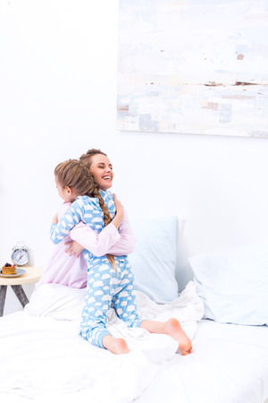 happy mother and daughter hugging in bedroomの写真素材