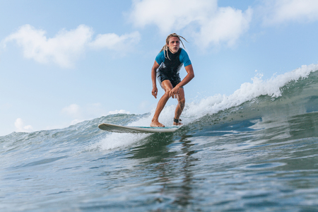 man with dreadlocks riding wave on surf board in oceanの写真素材