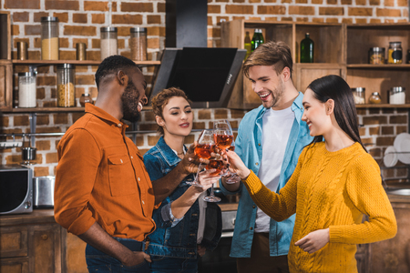 happy young multiethnic friends clinking wine glasses at homeの写真素材