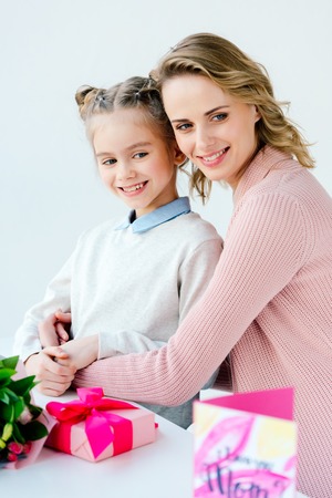 Portrait of happy mother hugging little daughter with presents on table, happy mothers day conceptの写真素材