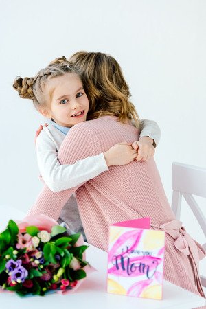 Kid and mother hugging each other with gifts on table, mothers day holiday conceptの写真素材