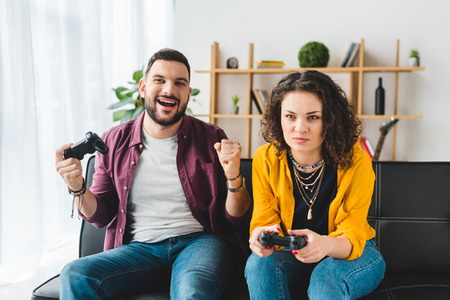 Young couple playing video game with joysticks
